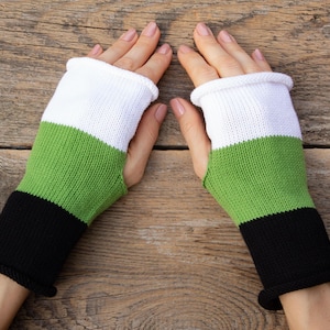 May include: A pair of fingerless gloves with a black, green, and white striped pattern. The gloves are made of knitted fabric.