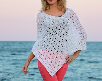 Può includere: Poncho bianco all'uncinetto con un delicato motivo traforato. Il poncho è indossato sopra un paio di pantaloni rosa corallo.