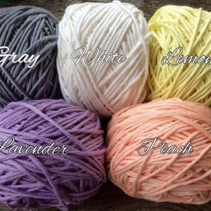 May include: Five balls of yarn in different colors: gray, white, lemon yellow, lavender, and peach.