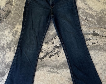 May include: Dark wash denim jeans with a classic five-pocket design. The jeans have a mid-rise waist and a slight flare at the hem. The jeans are made of a durable denim fabric and feature a button and zipper closure.
