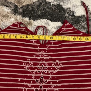 May include: Red and white striped halter top with embroidered floral design. The top has a measurement of approximately 18 inches across the top. The straps are thin and adjustable. The top is made of a soft, lightweight material.