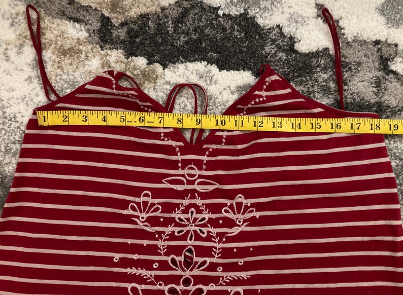May include: Red and white striped halter top with embroidered floral design. The top has a measurement of approximately 18 inches across the top. The straps are thin and adjustable. The top is made of a soft, lightweight material.