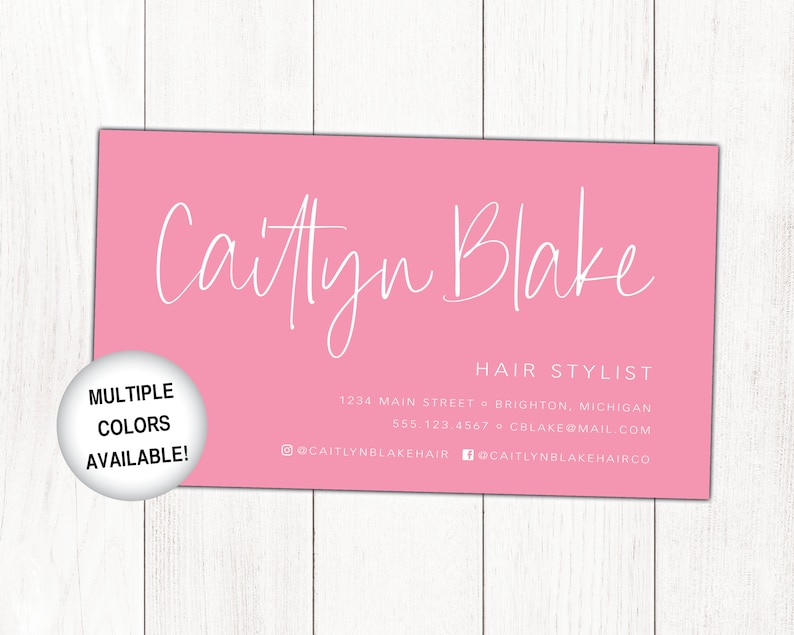May include: Pink business card with white text for a hair stylist named Caitlyn Blake. The card includes the business's address, phone number, email address, and social media handles. A white circle with black text reads "Multiple Colours Available!"