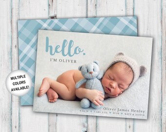 May include: A baby boy announcement card with a blue plaid background. The card features a photo of a newborn baby boy sleeping with a knitted teddy bear. The text on the card reads "hello. I'm Oliver" and includes the baby's name, birthdate, weight, length, and parents' names.