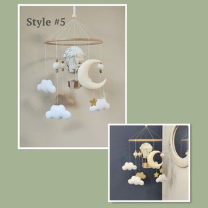 May include: A white and beige baby mobile with a hot air balloon, clouds, a crescent moon, and stars. The mobile is hanging from a wooden ring.