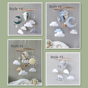 May include: Four different styles of baby mobile featuring a hot air balloon, clouds, stars, and a moon. The mobiles are made of felt and wood. Style #1 has a yellow sun, Style #2 has a blue moon, Style #3 has a gray moon, and Style #4 has a green moon.