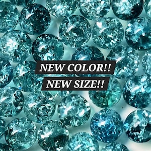 May include: A collection of round, teal-colored glass beads with a crackled texture throughout. The beads are arranged in a dense pattern. Overlaid on the center of the image are two black rectangular banners with white text reading NEW COLOR!! NEW SIZE!!