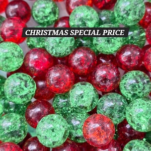 May include: A collection of round, crackle-textured glass beads in vibrant red and green colors. The beads feature a glossy finish with internal fractures that catch the light. A black rectangular label with the white text CHRISTMAS SPECIAL PRICE is overlaid across the center of the bead pile.
