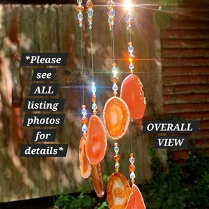 May include: A hanging wind chime featuring a circular wooden frame with multiple strands of clear and amber-colored beads. Several polished orange agate slices are suspended from the beads. Text on the image reads: *Please see ALL listing photos for details* and OVERALL VIEW.