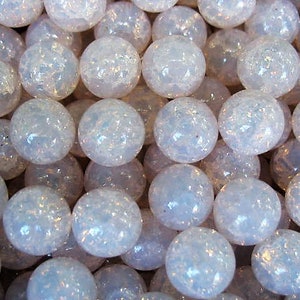 May include: A close-up of a group of iridescent white glass marbles. The marbles are arranged in a random pattern and have a slightly textured surface.