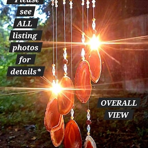 May include: A hanging wind chime featuring multiple translucent orange agate slices suspended from a circular wooden frame by thin wires. The design includes clear and amber-colored beads interspersed along the strings. Text reads: *Please see ALL listing photos for details* and OVERALL VIEW.