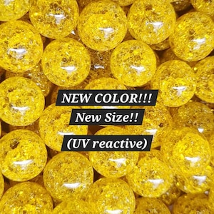 May include: A close-up shot showcases a collection of numerous yellow, spherical objects with a textured, cracked appearance. The text "NEW COLOR!!! New Size!! (UV reactive)" is overlaid on the image. These objects appear to be decorative or collectible items.