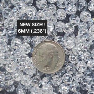 May include: A collection of clear, round, crackle-textured beads measuring 6mm (.236 inches) in diameter. A silver-colored United States dime coin is placed among the beads for scale, with text overlay reading NEW SIZE!! 6MM (.236").