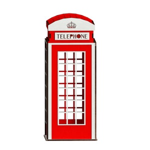 May include: Red telephone booth with a white roof and the word "TELEPHONE" in white letters. The booth has a small crown on the roof.