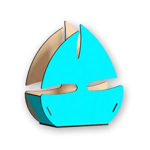 Puede incluir: Un porta servilletas de madera con forma de velero, pintado en azul brillante. El porta servilletas tiene un diseño recortado en forma de velero.