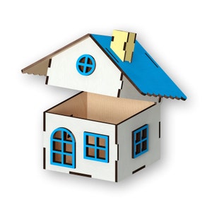 Könnte beinhalten: Eine holzfarbene, hausförmige Box mit blauem Dach und Fensterrahmen. Das Haus hat ein abnehmbares Dach, einen gelben Schornstein und einen Innenraum aus Naturholz. Die Fenster sind blau umrandet.