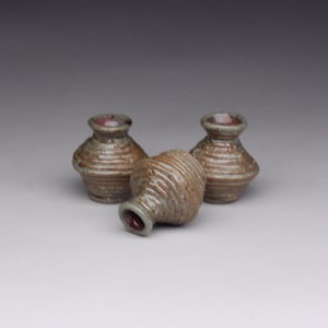May include: Three small, ceramic pots with a brown and green glaze. The pots are stacked on top of each other.
