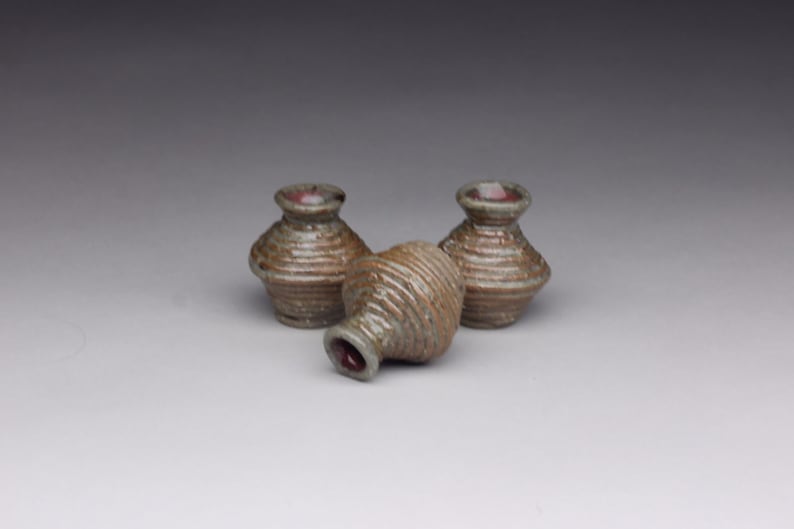 May include: Three small, ceramic pots with a brown and green glaze. The pots are stacked on top of each other.