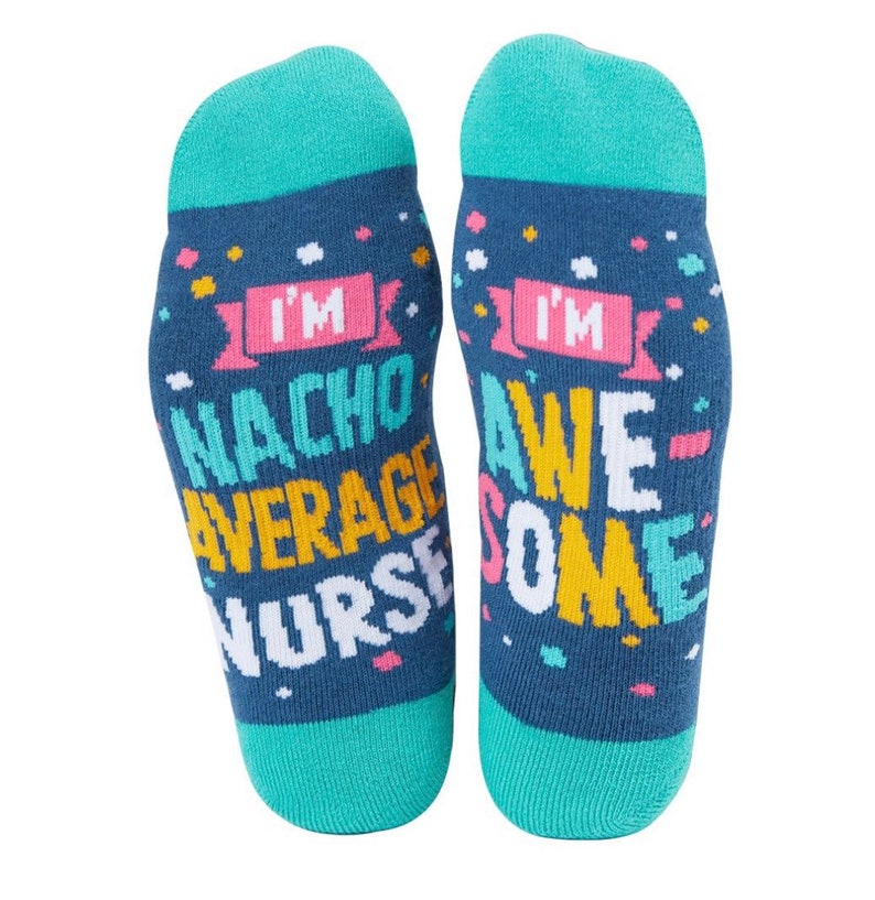 Op de afbeelding: Een paar blauwe sokken met een kleurrijk ontwerp. De sokken zeggen "I'm Nacho Average Nurse" en "I'm Awesome".