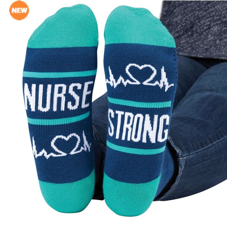 Op de afbeelding: Een paar blauwe en turquoise sokken met een witte hartslaggrafiek en de tekst "NURSE STRONG".