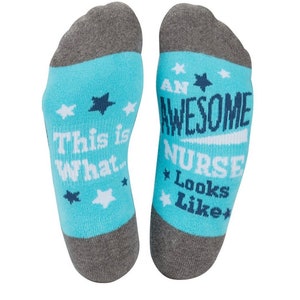 Op de afbeelding: Een paar blauwe en grijze sokken met witte sterren en de tekst "This is what an awesome nurse looks like" erop.