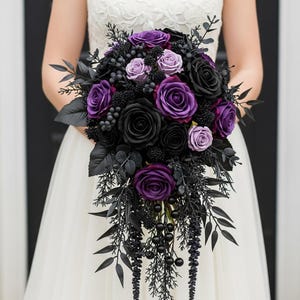 May include: A cascading bridal bouquet with black and purple roses, berries, and leaves. The arrangement features deep purple and black blooms, with dark foliage. The bouquet is held against a white dress, creating a striking contrast.