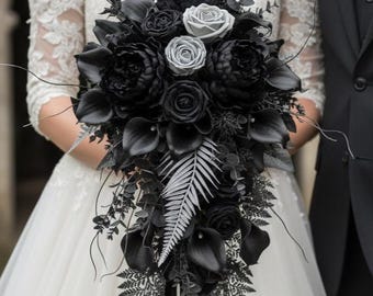 May include: A cascading bridal bouquet featuring black and silver flowers, including roses, calla lilies, and ferns. The bouquet is held by a person wearing a white off-the-shoulder lace dress. Black ribbon accents the bouquet.