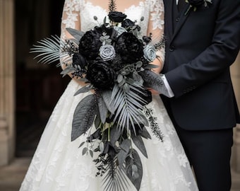 May include: A bridal bouquet featuring black and gray flowers and foliage. The bouquet includes large, dark peonies, roses, and various leaf shapes. The bride is wearing a white lace wedding dress, and the groom is wearing a black suit.