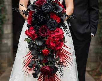 Puede incluir: Un ramo de novia con una cascada de flores rojas y negras, incluyendo rosas y calas. El ramo está acentuado con hojas negras y hojas de palma rojas, atado con una cinta negra. Un novio con un traje negro y un prendido rojo está cerca.