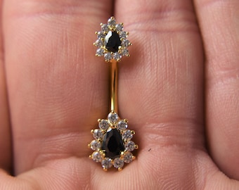 May include: Gold belly button ring with two teardrop-shaped black stones surrounded by clear rhinestones.