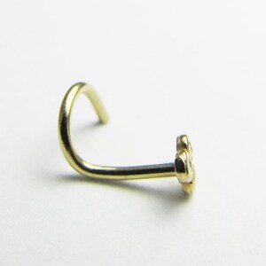 May include: A gold nose ring with a small flower design.