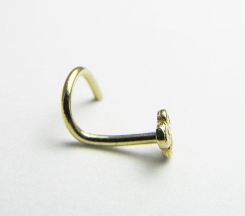May include: A gold nose ring with a small flower design.