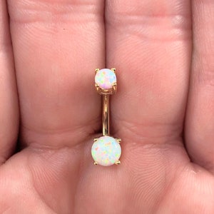 May include: Gold belly button ring with two white opal stones.