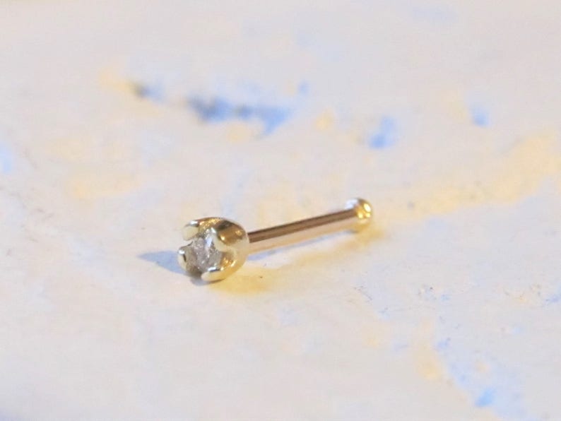 May include: A gold nose ring with a small, clear diamond.