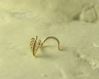 Könnte beinhalten: Ein goldener Nasenring mit einem Blattdesign. Der Ring ist gebogen und hat ein kleines, zartes Blatt am Ende.