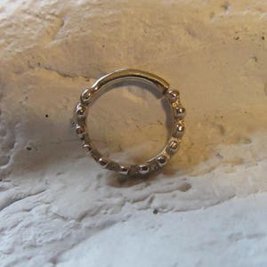 May include: A gold-toned beaded ring with a seamless, circular design. The ring is made of metal and has a smooth, polished finish.