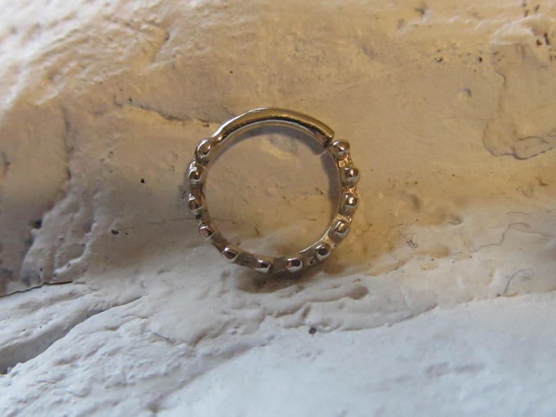 May include: A gold-toned beaded ring with a seamless, circular design. The ring is made of metal and has a smooth, polished finish.