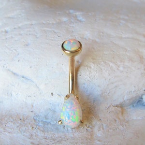 May include: Gold belly button ring with a round opal top and a teardrop opal bottom.