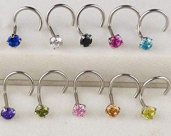May include: A collection of ten nose rings with curved posts. Each ring features a small, round gemstone in a different color, including blue, clear, black, pink, and turquoise. Additional colors include purple, green, pink, orange, and yellow.