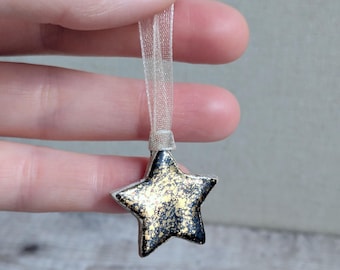 One very small handmade ceramic star hanging decoration, dark blue with gold splatter
