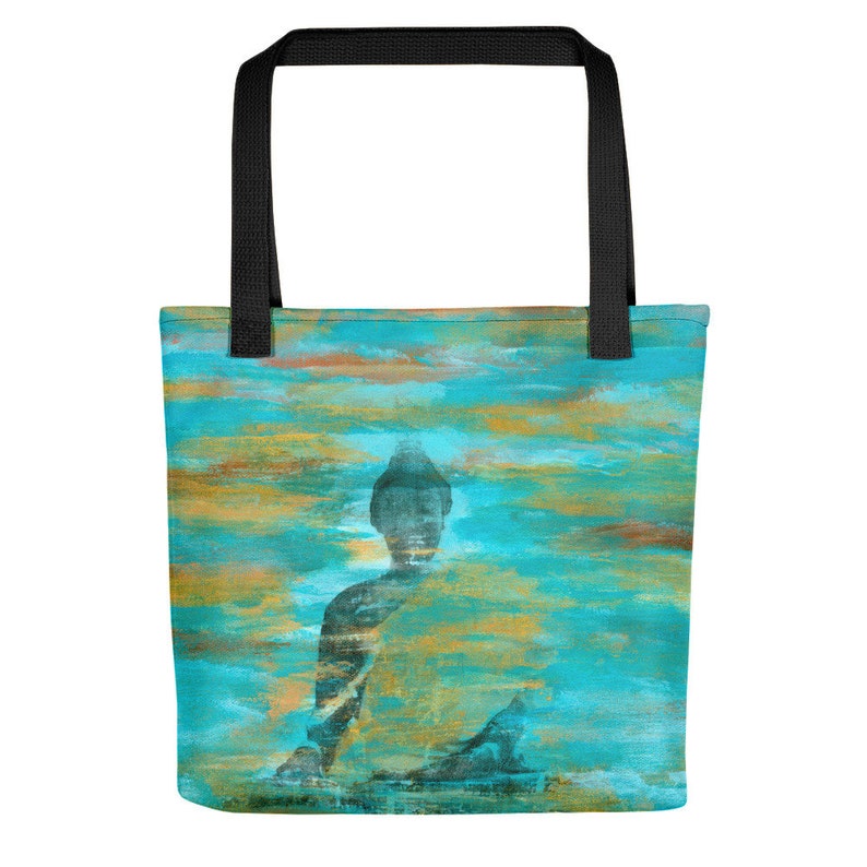 May include: A tote bag with a blue and gold abstract design featuring a silhouette of a meditating Buddha. The bag has black handles.