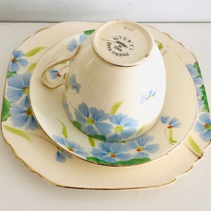 K&ouml;nnte beinhalten: Ein dreiteiliges Teeset mit Blumenmuster. Das Set besteht aus einer Tasse, einer Untertasse und einem gr&ouml;&szlig;eren Teller. Tasse und Untertasse haben ein blaues und gr&uuml;nes Blumenmuster mit goldener Verzierung. Der gr&ouml;&szlig;ere Teller hat ein &auml;hnliches Muster, ist aber gr&ouml;&szlig;er. Auf der R&uuml;ckseite der Tasse steht "PHOENIX WARE MADE IN ENGLAND T.T. & S. LTD. 322".