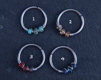 May include: Twelve silver hoop earrings with different colored beads. Each hoop is numbered 1 through 12.