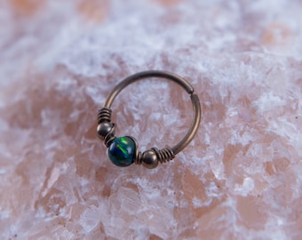 May include: A green opal gemstone set in a silver hoop earring with a beaded design.