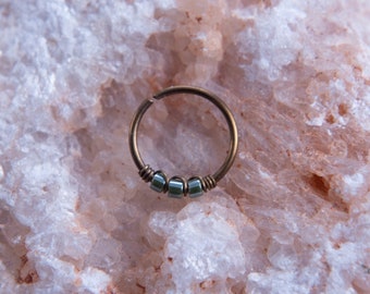 May include: A gold hoop earring with a row of four small, square, iridescent green beads.
