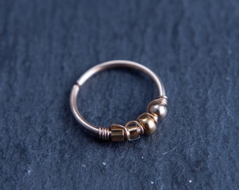 May include: A silver hoop earring with gold beads and a silver charm.