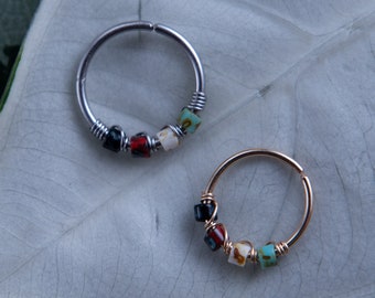 May include: Two silver and gold hoop earrings with colorful glass beads. The earrings are on a white background.