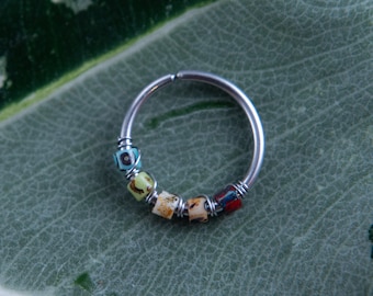 May include: A silver hoop earring with colorful glass beads. The beads are in a rainbow pattern, with blue, green, yellow, orange, and red beads.