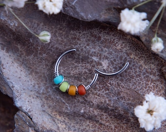 May include: A silver hoop earring with five colorful beads. The beads are turquoise, green, yellow, orange, and red.