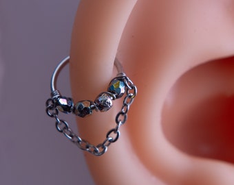 May include: A silver hoop earring with a chain and iridescent beads. The earring is worn in the upper cartilage of the ear.